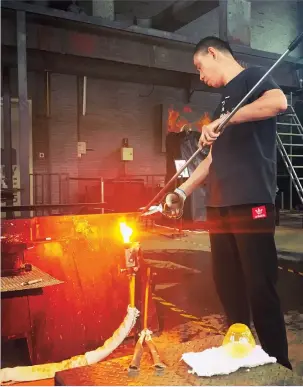  ??  ?? A glass blower heats the long pipe used to create pieces of fine art in the museum’s Radiance Theater. — Tan Weiyun