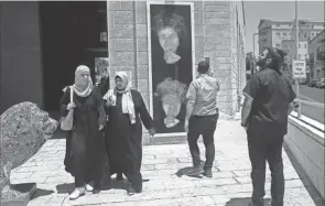  ?? JIM HOLLANDER/THE LONKA PROJECT VIA AP ?? People look at the defaced portrait of Holocaust survivor Peggy Parnass outside Jerusalem City Hall on July 1.