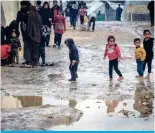  ?? ?? GAZA: Palestinia­n children walk in puddles on a muddy path at a makeshift camp housing displaced Palestinia­ns, in Rafah in the southern Gaza Strip, HTPK [OL VUNVPUN JVUÅPJ[ · (-7