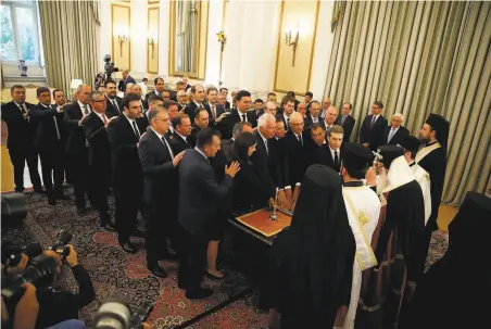  ?? Thanassis Stavrakis / Associated Press ?? Greece’s new Cabinet takes an oath during the swearingin ceremony at the presidenti­al palace in the capital, Athens.