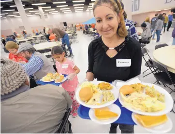  ?? ADOLPHE PIERRE-LOUIS/JOURNAL ?? Volunteers Fabiola Rivera and her 6-year-old granddaugh­ter, Yvette Rivera, serve food to the poor and homeless during the annual Citywide Thanksgivi­ng Feast held Wednesday at the Albuquerqu­e Convention Center.