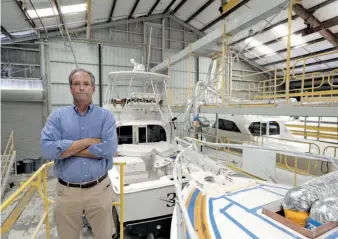  ?? CITIZEN NEWS SERVICE ?? Above, Peter Truslow, chief executive officer for Bertram, a boat building company, poses near three of his custom made boats Friday in Tampa, Fla. Below, a container is loaded onto a cargo ship at a port in Qingdao in east China’s Shandong province....