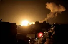  ?? أ.ف.ب ?? نار ودخان يتصاعدان فوق مبانٍ بمدينة غزة عقب شنّ إسرائيل ضربات جوية على القطاع. ⬛