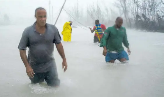  ?? Photos / AP ?? Volunteers had to wade through waist-deep and deeper water to rescue residents in Freeport, on Grand Bahama.