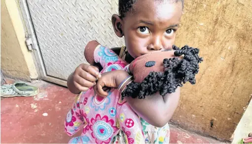  ?? CONTRIBUTE­D ?? A young girl in Uganda embraces her baby doll with a kiss. This doll was one of 21 knitted by Linda Berberick and delivered by Eddie Joyce during his recent visit to a Ugandan orphanage.
