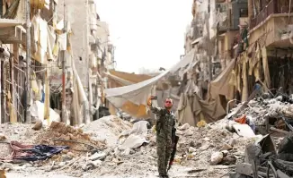  ??  ?? A fighter from Syrian Democratic Forces takes a selfie near a damaged site in Raqqa on Monday. (Reuters)