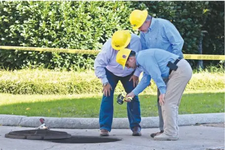  ?? STAFF PHOTO BY ROBIN RUDD ?? Electric Power Board personnel examine the scene of an undergroun­d electrical fire near City Hall. The fire Tuesday led to evacuation­s and road closures at the corner of East 11th Street and Lindsay Street by City Hall.