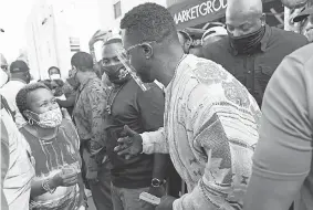  ?? LYNNE SLADKY/ AP ?? Rapper Sean “Diddy” Combs passes out $ 50 bills to residents in the Overtown neighborho­od of Miami on Tuesday. Various organizati­ons came together to also pass out gift cards and gift bags with essentials for those in need during the coronaviru­s pandemic.