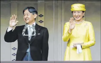  ?? Fumine Tsutabayas­hi The Associated Press ?? Japan’s Emperor Naruhito waves with Empress Masako during his first appearance before the public as emperor Saturday at the Imperial Palace in Tokyo.