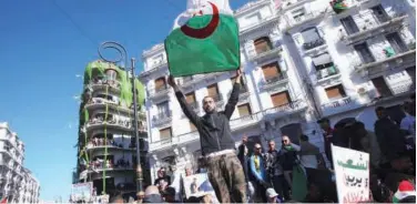  ?? File / Reuters ?? ↑ A demonstrat­or carries a national flag during a protest over Abdelaziz Bouteflika’s decision to postpone elections and extend his fourth term in office in Algiers.