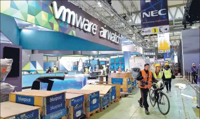  ?? LLUIS GENE / AFP ?? People walk past a stand of VMware at an industry expo in Barcelona, Spain. The company is undergoing a business transition to grow its cloud products and services, especially in countries like China.