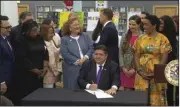  ?? (AP/State of Illinois) ?? Gov. J.B. Pritzker signs a bill on Monday at Harold Washington Library’s Thomas Hughes Children’s Library in downtown Chicago.