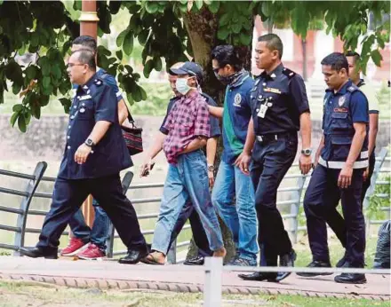  ?? FILE PIC ?? Police officers with one of the suspects in the Darul Quran Ittifaqiya­h religious school fire in Kampung Datuk Keramat, Kuala Lumpur, last month. The thought that children of such tender age could muster a fiery plan is in itself frightenin­g.