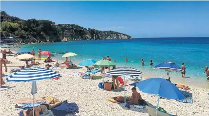  ?? A busy day on the beach in Portoferra­io ?? UMBRELLA FUNDS: