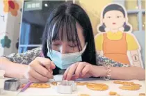  ?? ?? A customer cuts a biscuit in Beijing, China.