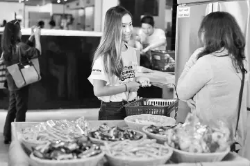  ??  ?? This picture shows a volunteer (left) helping out a customer at OzHarvest Market, a recycled food supermarke­t, in Sydney. — AFP photo