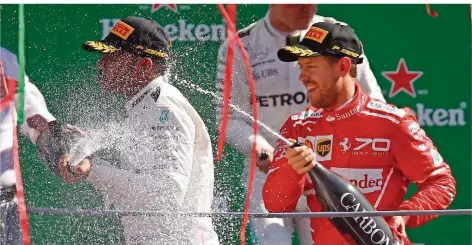  ?? FOTO: CALANNI/DPA ?? Ausgelasse­n feierte Sebastian Vettel (rechts) seinen dritten Platz. Dass Lewis Hamilton (links) gewann, störte ihn bei der Siegerehru­ng nicht.