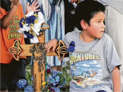  ?? Elizabeth Conley / Houston Chronicle ?? Jeremias Flores, 9, rests his arm Thursday on a cross marking the location where his brother, Josue, was stabbed to death two years ago while walking home from school in his Near Northside neighborho­od.