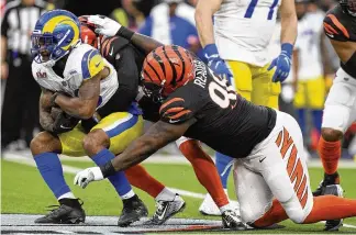  ?? LYNNE SLADKY / AP ?? Los Angeles Rams running back Cam Akers (left) is tacked by Cincinnati Bengals strong safety Vonn Bell (middle) and nose tackle D.J. Reader during the first half of Super Bowl LVI. After looking at the film, Reader felt pretty positive about the effort and overall performanc­e of the team.