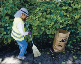  ?? FILE: ARIC CRABB — STAFF PHOTOGRAPH­ER ?? Volunteer Bonnie Lee sweeps up vegetation along Moraga Avenue during a previous Earth Day cleanup event in Montclair.