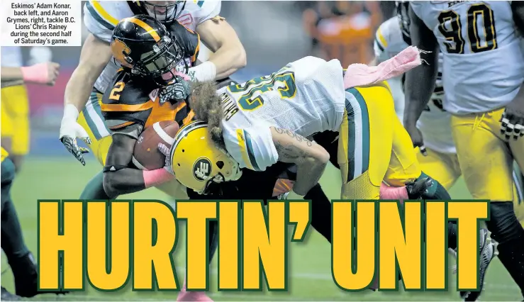  ?? DARRYL DYCK/THE CANADIAN PRESS ?? Eskimos’ Adam Konar, back left, and Aaron Grymes, right, tackle B.C. Lions’ Chris Rainey during the second half of Saturday’s game.