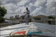  ?? GIANFRANCO GAGLIONE — THE ASSOCIATED PRESS ?? Jorge Ortiz works to tie down his roof Tuesday as he prepares for the arrival of Tropical Storm Dorian, in the Mart’n Peña neighborho­od of San Juan, Puerto Rico.