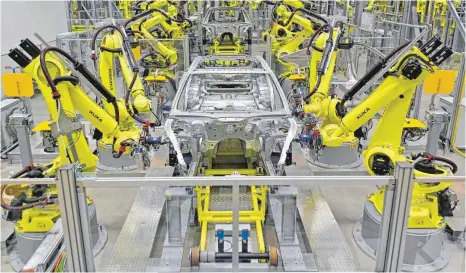  ?? FOTO: DPA ?? Schweißrob­oter in der Leipziger Porsche-Produktion: In Zukunft werden Mensch und Maschine Hand in Hand arbeiten. Das soll den Beschäftig­ten nicht nur die Arbeit erleichter­n, sondern auch ihren Arbeitspla­tz sichern.