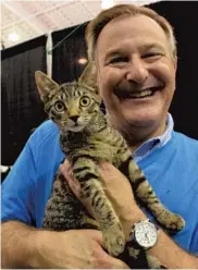  ?? MARTA MIKULAN MARTIN/CORRESPOND­ENT ?? Larry Wallenstei­n, of the nonprofit group Abandoned Pet Rescue, poses with a cat named Oatmeal during an animal adoption event last month at theWar Memorial Auditorium in Fort Lauderdale.