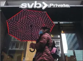  ?? (AP/Jeff Chiu) ?? A pedestrian carries an umbrella Tuesday while walking past a Silicon Valley Bank Private branch in San Francisco.