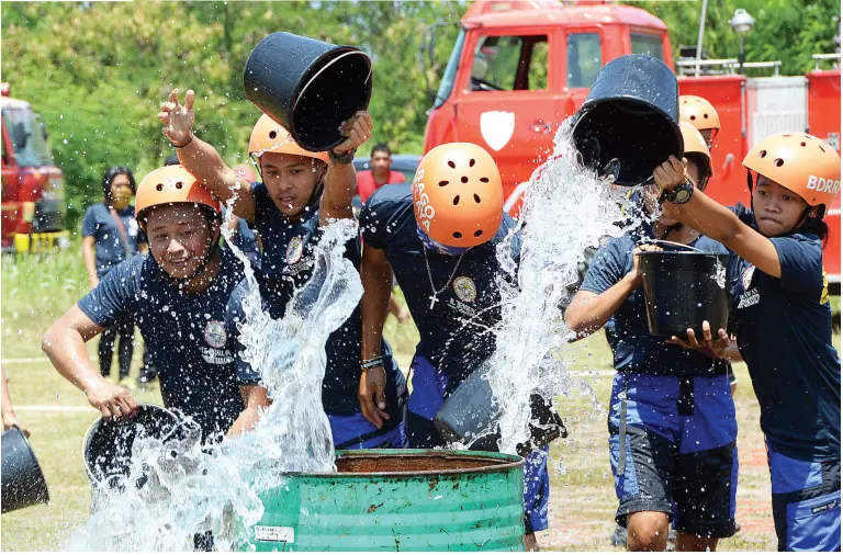  ??  ?? BARANGAY disaster volunteers join hands in filling up the drum with water during the bucket relay as part of the Industrial and Barangay Firefighte­rs Combat Challenge held at the Crocodile Park Complex grounds on Saturday. BING GONZALES