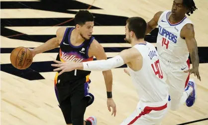  ?? Photograph: Matt York/AP ?? Phoenix Suns guard Devin Booker looks to pass as Los Angeles Clippers center Ivica Zubac (40) and guard Terance Mann (14) defend during the first half of Wednesday’s game.