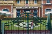  ?? DAVID MCNEW — GETTY IMAGES ?? An employee cleans the grounds behind the closed gates of Disneyland Park on March 14, the first day of its shutdown.