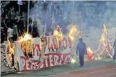  ??  ?? AP Panathinai­kos fans burn an Olympiakos banner in front of stands during a Greek Super League soccer match at the Athens Olympic Stadium in Athens, Greece, on March 17, 2019.