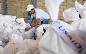  ?? FERNANDO VERGARA /ASSOCIATED PRESS ?? A Venezuelan volunteer readies a bag of USAID humanitari­an aid for storage at a warehouse next to the Tienditas Internatio­nal Bridge, near Cucuta, Colombia, on Friday.