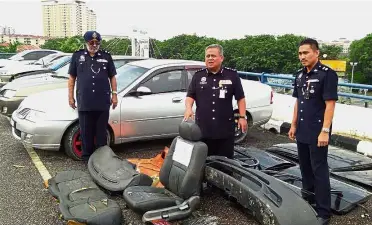  ??  ?? DCP Abdul Jalil (centre) showing car components which had been cannibalis­ed by the Dino Gang. For spare parts: