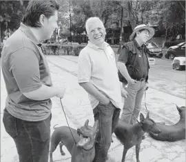  ??  ?? MIGUEL RETANA, center, with fellow Xoloitzcui­ntle owners in Mexico City. He has 46 of the dogs and says they connect him back to his Mexican identity.