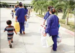  ?? VIREAK MAI ?? Women prisoners carry their possession­s out of Prey Sar after being released in 2015. A new report highlights the narratives of Cambodian women convicted of homicide.