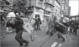  ?? ERIC TSANG/HK01VIA AP ?? A masked protester runs from police officers during a protest Saturday in Hong Kong.