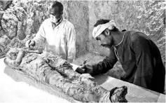  ??  ?? Egyptian archaeolog­ical technician­s restore a mummy wrapped in linen. — AFP photo