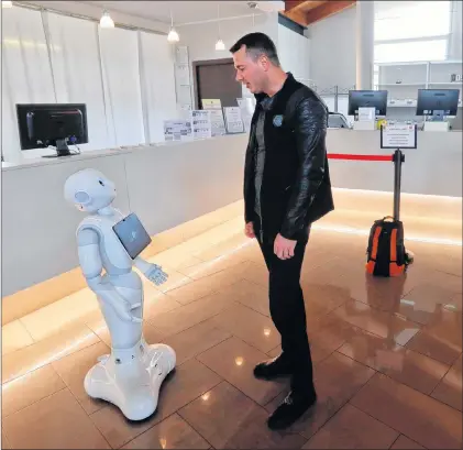  ?? AP PHOTO ?? Mihail Slanina, a guest from Moldova, asks robot Robby Pepper for informatio­n at the front desk of a hotel in Peschiera del Garda, northern Italy, on March 12.