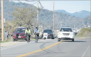  ?? SHERRY LAVARS — MARIN INDEPENDEN­T JOURNAL ?? A car passes bicyclists on Paradise Drive in Corte Madera on Nov. 17. The town is working on plans to improve a section of the road for people walking and riding bikes.