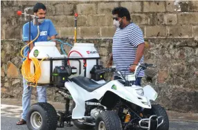  ??  ?? Young inventors with a mobile machine to spray disinfecta­nt