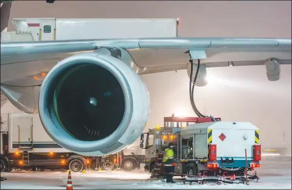  ?? SHUTTERSTO­CK IMAGES ?? Workers refuel a passenger aircraft. As the aviation industry tries to erase its carbon emissions by 2050, mostly by using huge quantities of cleaner jet fuel, it faces huge obstacles. Last year, the world’s commercial air carriers consumed 90 billion gallons of jet fuel.