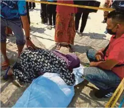  ??  ?? ISTERI mangsa, Zainab Embong tidak dapat menahan kesedihan dan memeluk jenazah suaminya di Pantai Teluk Ketapang, semalam.