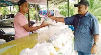  ??  ?? DAUD (kiri) melayan pelanggan yang membeli laksa kebok di Kampung Landak, Kupang.