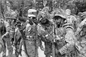  ?? Sgt. 1st Class Justin A. Naylor ?? U.S. Army Spc. Vuongkhang Luong of Adairsvill­e (left) looks down the sights of a weapon during a training exercise his “Black Lions” unit participat­ed in with the Japan Ground SelfDefens­e Force on June 24.