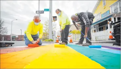  ?? Stephanie Zollshan The Associated Press ?? Matt Pevzner, left, Tim Hosier, center, and Darryl Austin of the Great Barrington Highway Department paint over the crosswalk on Elm Street with brightly colored rainbow stripes Wednesday in Great Barrington, Mass. In solidarity with the worldwide movement of displaying rainbow colors as a sign of hope amid the COVID-19 crisis, the crew planned to paint six crosswalks.