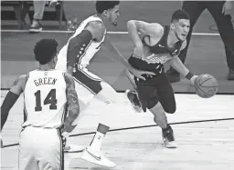  ?? PATRICK BREEN/THE REPUBLIC ?? Suns guard Devin Booker drives on the 76ers' Tobias Harris during the first half at Phoenix Suns Arena on Feb. 13.