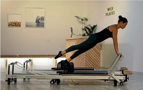  ?? SUPPLIED ?? Trainer Laura Mohi demonstrat­es a Pilates move on the intriguing reformer machine.