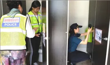  ??  ?? A hidden-camera search squad, consisting of student and citizen volunteers, scan a restroom near a public pool in Changwon.